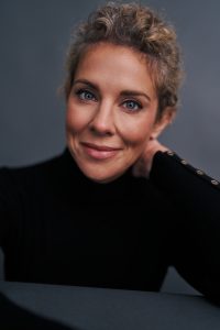 Heidi Rew, Atlanta Actor, Host and Voice Over Actor - headshot, curly hair pulled back 